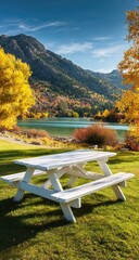 White picnic table in autumn park by a lake. Mountains in background