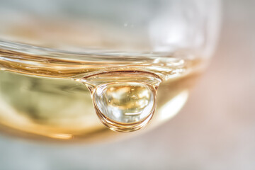 Clear oil drop suspended on glass surface, abstract macro photography with smooth texture and warm golden color, creating calm and reflective mood in minimalistic style