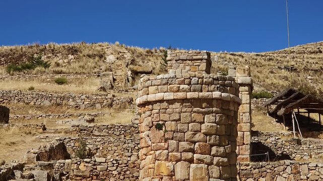 A captivating pan shot showcases the well-preserved funerary towers of Chullpas de Molloco near Acora, Peru, highlighting their ancient stone masonry against a vast, mountainous landscape.