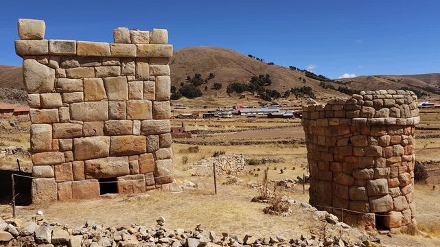 A captivating pan shot showcases the well-preserved funerary towers of Chullpas de Molloco near Acora, Peru, highlighting their ancient stone masonry against a vast, mountainous landscape.