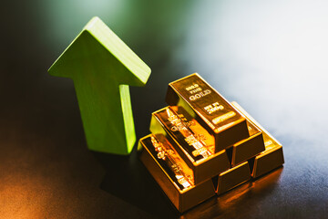 Gold bars forming a pyramid shape with a green arrow pointing up, the idea of ​​the current rising gold price.