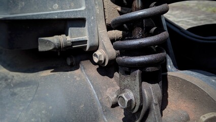 A close-up shot of a motorcycle's shock absorber with noticeable oil leakage, indicating a need for repair or maintenance.