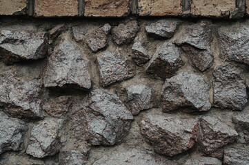 A close-up view of a rough stone wall, showcasing natural, uneven rocks fitted together.