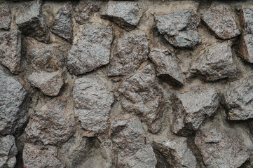 A close-up view of a rough stone wall, showcasing natural, uneven rocks fitted together.