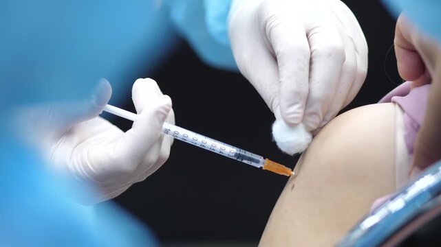 Healthcare worker administering a vaccine injection to a patient&rsquo;s arm, close-up view