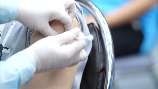 Healthcare worker administering a vaccine injection to a patient&rsquo;s arm, close-up view