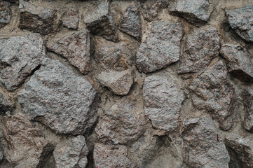 A close-up view of a rough stone wall, showcasing natural, uneven rocks fitted together.
