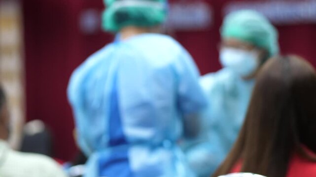 Blurred view of healthcare workers in protective clothing preparing to administer vaccines