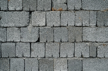 A plain gray cinder block wall with a rough, industrial texture