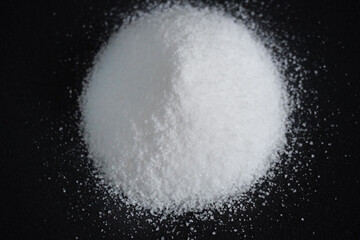 Granulated sugar in a bowl on black background 