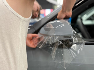 The process of installing PPF, armored film on the car. PPF is a polyurethane, protective film that protects the paint from scratches. Car wrapping, tuning, styling. Close-up, selective focus. 