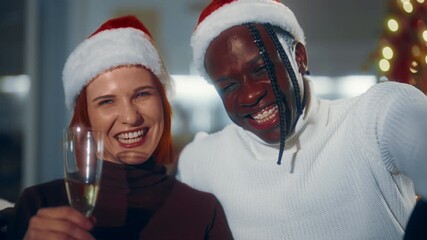 Black man and his charming Caucasian girlfriend celebrating Christmas Eve. Portrait of happy biracial lovers with glasses of champagne at home, merry Xmas party, joyful people smiling and laughing