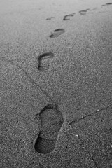 Mysterious Footprints on Wet Sand Captured in Black and White Evoking Solitude and Exploration