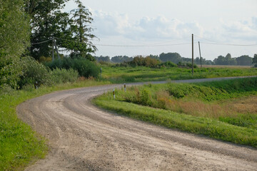 Naklejka premium winding gravel road in Latvia countryside in summer