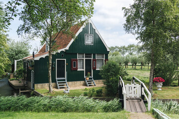 Quaint Green Dutch Cottage with Rustic Bridge Surrounded by Lush Trees and Tranquil Countryside Atmosphere