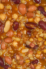 A close-up shot shows a thick soup made of various beans, with pieces of bacon and vegetables