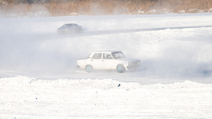 Racing on cars in winter. winter car racing. A white car in a skid and a snow haze turns sharply at the turn of the highway. © Антон Скрипачев