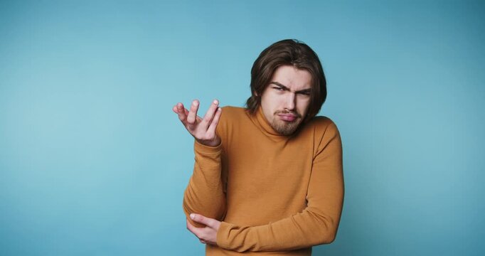footage of young confused man gestures with an uncertain expression on blue background