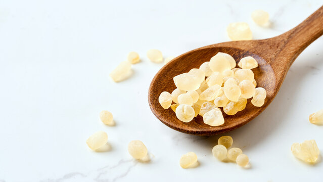 closeup pile of mastic gum or tear of chios in wood spoon white table food background with copy space