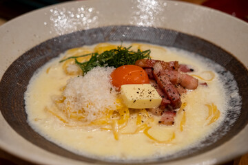 Spaghetti Carbonara with bacon and egg yolk served on a plate. Soft Focus.