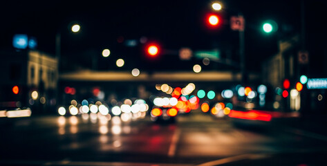 Blurred city street scene at night featuring glowing car lights and colorful traffic signals, capturing the dynamic movement and energy of urban nightlife.