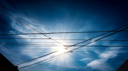 Fototapeta premium Low angle view looking up at metal electricity pylons against a clear bright blue sky; electricity pylons or towers with cables and wires; concept electricity transmission, electrical infrastructure