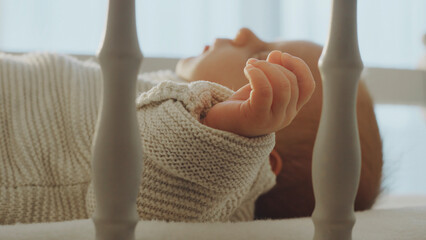Baby sleeping peacefully in crib wearing knitted sweater