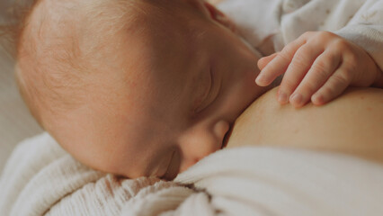 Newborn baby sleeping while breastfeeding on mother