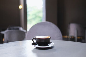 Closeup image of a cup of hot coffee on the table in cafe
