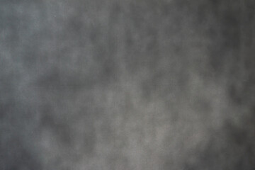 A close-up of a dark, textured surface with a subtle. The varying shades of grey and black create a dramatic and moody background, perfect for use as a backdrop or abstract wallpaper.