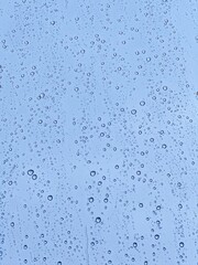 Raindrops on glass illustrating climate change impact, extreme weather patterns, and shifting precipitation trends in blue hues