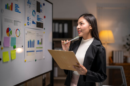 woman is standing in front of a white board with a pen in her hand