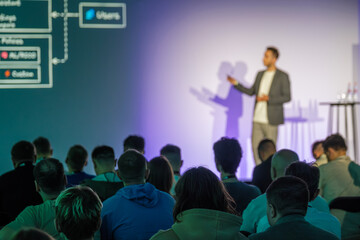 Conference presentation in progress with speaker and audience attending an educational session.