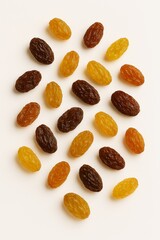 Assorted colorful raisins scattered on a bright white background, healthy snack.