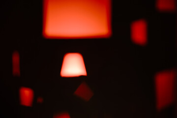 Modern abstract art with glowing red geometric shapes, including a prominent trapezoid. Soft, blurry lights create a futuristic and warm atmosphere.
