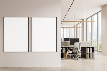 Two vertical blank poster mockups on a clean wall next to a bright modern office interior with desks and large windows overlooking a cityscape view. 3D Rendering