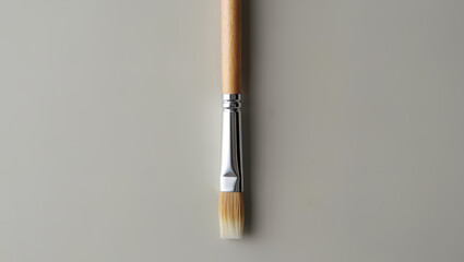 Simple Flat Head Paintbrush with Wooden Handle and Metal Ferrule on a Solid Gray Background