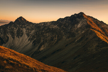 Naklejka premium Majestic mountain range bathed in the warm glow of sunset