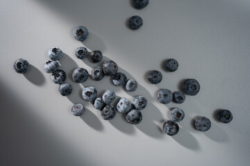 Fresh blueberries scattered artistically on a soft gray surface showcasing their rich colors and textures in natural light