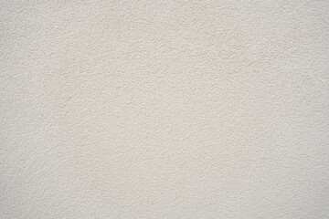 Subtle texture of a light beige wall reveals layers and depth in early morning sunlight with soft shadows playing across the surface