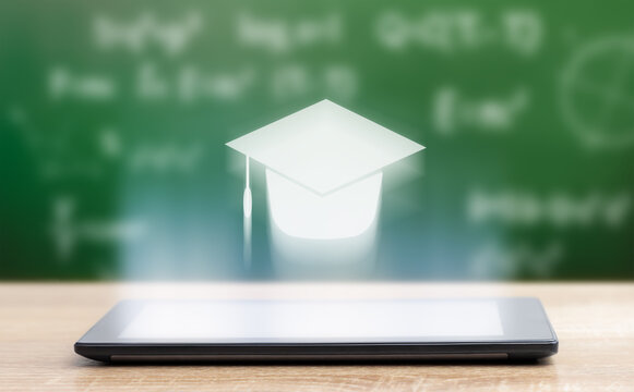 digital tablet and hologram in the form of a graduation cap on the background of a school board. education concept