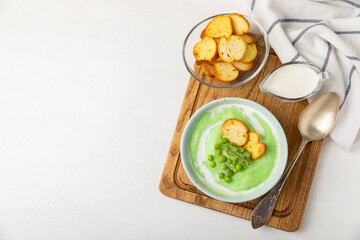 Green pea soup on a wooden table. Fresh pea soup bowl. Delicious healthy cream soup in a bowl with green peas and croutons. Healthy vegan puree. Copy space. Space for text.