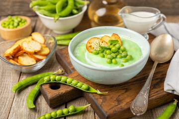 Green pea soup on a wooden table. Fresh pea soup bowl. Delicious healthy cream soup in a bowl with green peas and croutons. Healthy vegan puree. Copy space. Space for text.