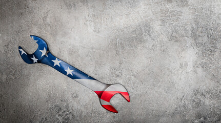 wrench with american flag overlay on concrete background with copy space. concept labor day USA
