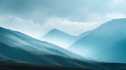Fototapeta premium Serene Mountain Range Landscape with Fog and Dramatic Cloudy Sky in Blue Tones