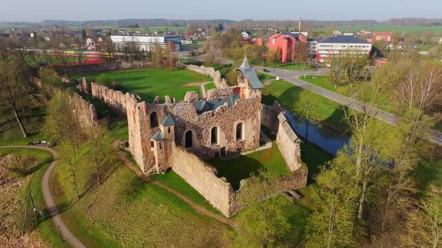 Historic castle ruins captured in slow drone orbit during spring, Dobele, Latvia
