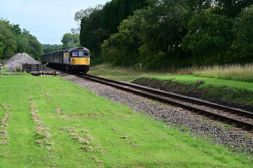Obraz premium Vintage class 33 diesel locomotive pulling a passenger train through the English Countryside. 