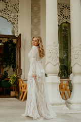  Beautiful slim blonde poses in boho wedding dresses and an embroidered corset on a summer terrace.