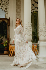  Beautiful slim blonde poses in boho wedding dresses and an embroidered corset on a summer terrace.