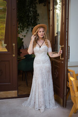  Beautiful slim blonde poses in boho wedding dresses and an embroidered corset on a summer terrace.